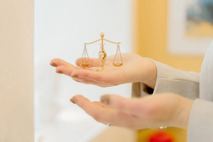 Balança da justiça sobre uma mão