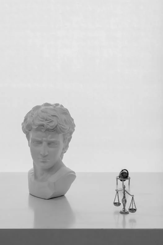 Escultura clássica ao lado de uma balança da justiça